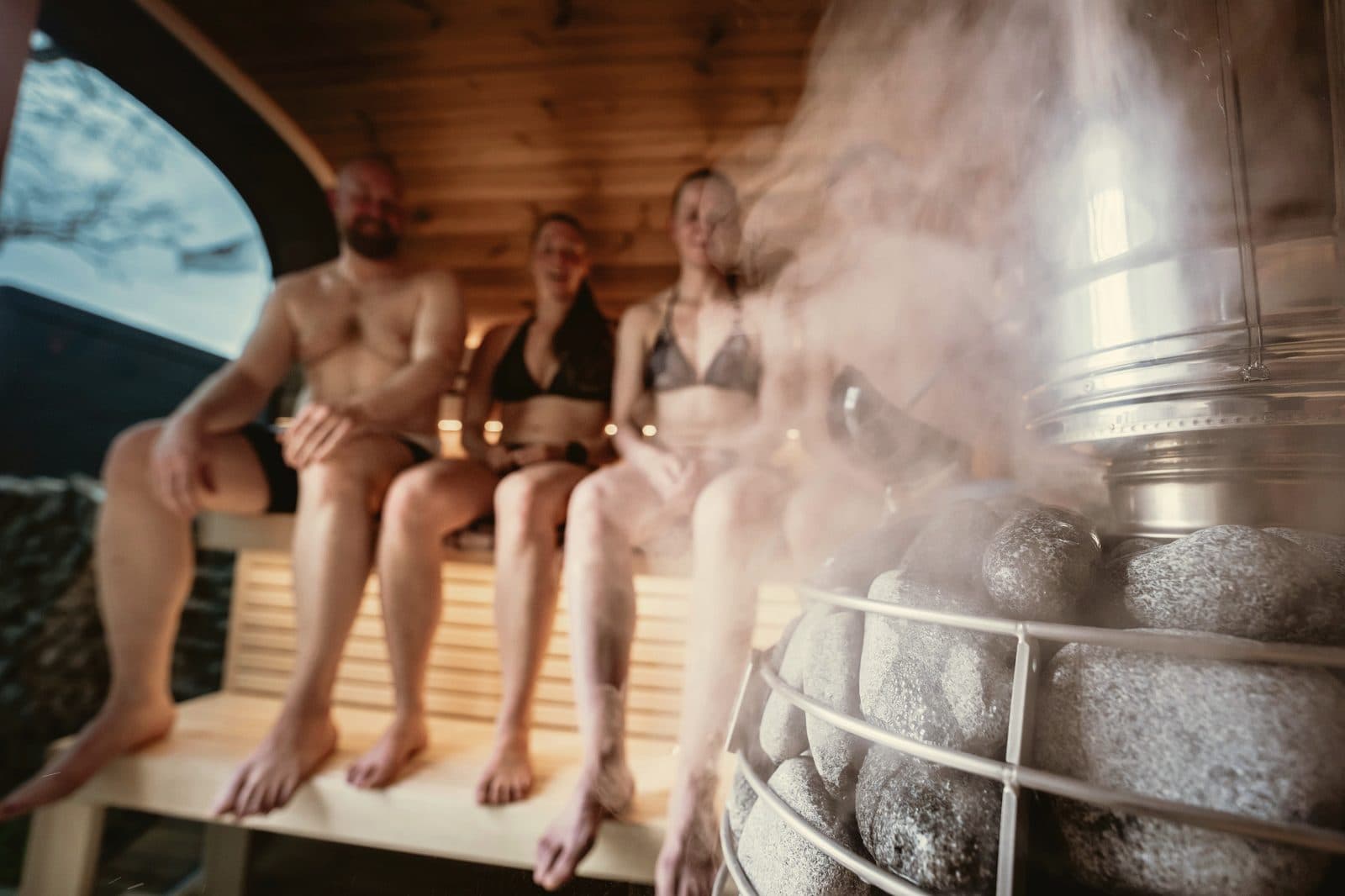 Group enjoying a barrel sauna session with steam rising in the open air