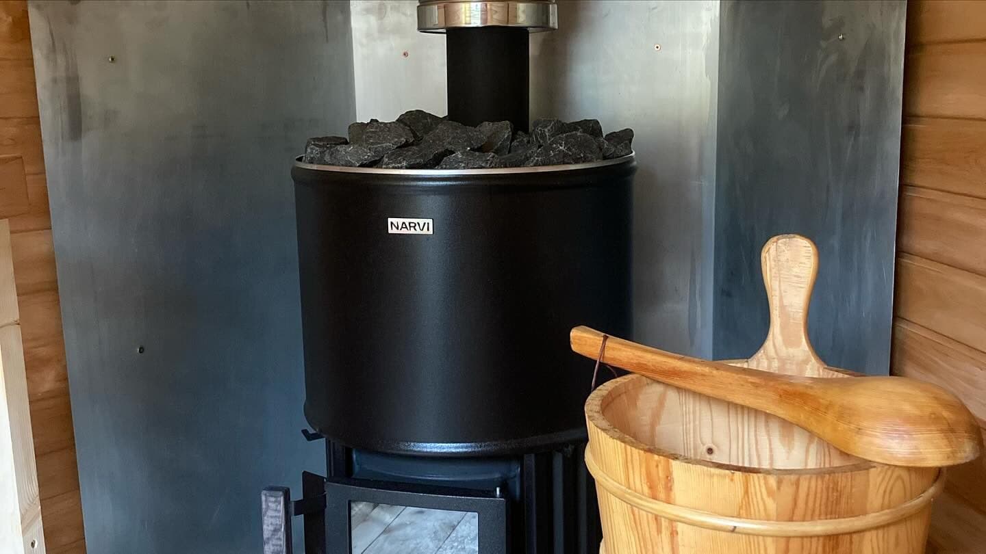 Narvi wood-fired sauna stove with stones and wooden bucket and ladle
