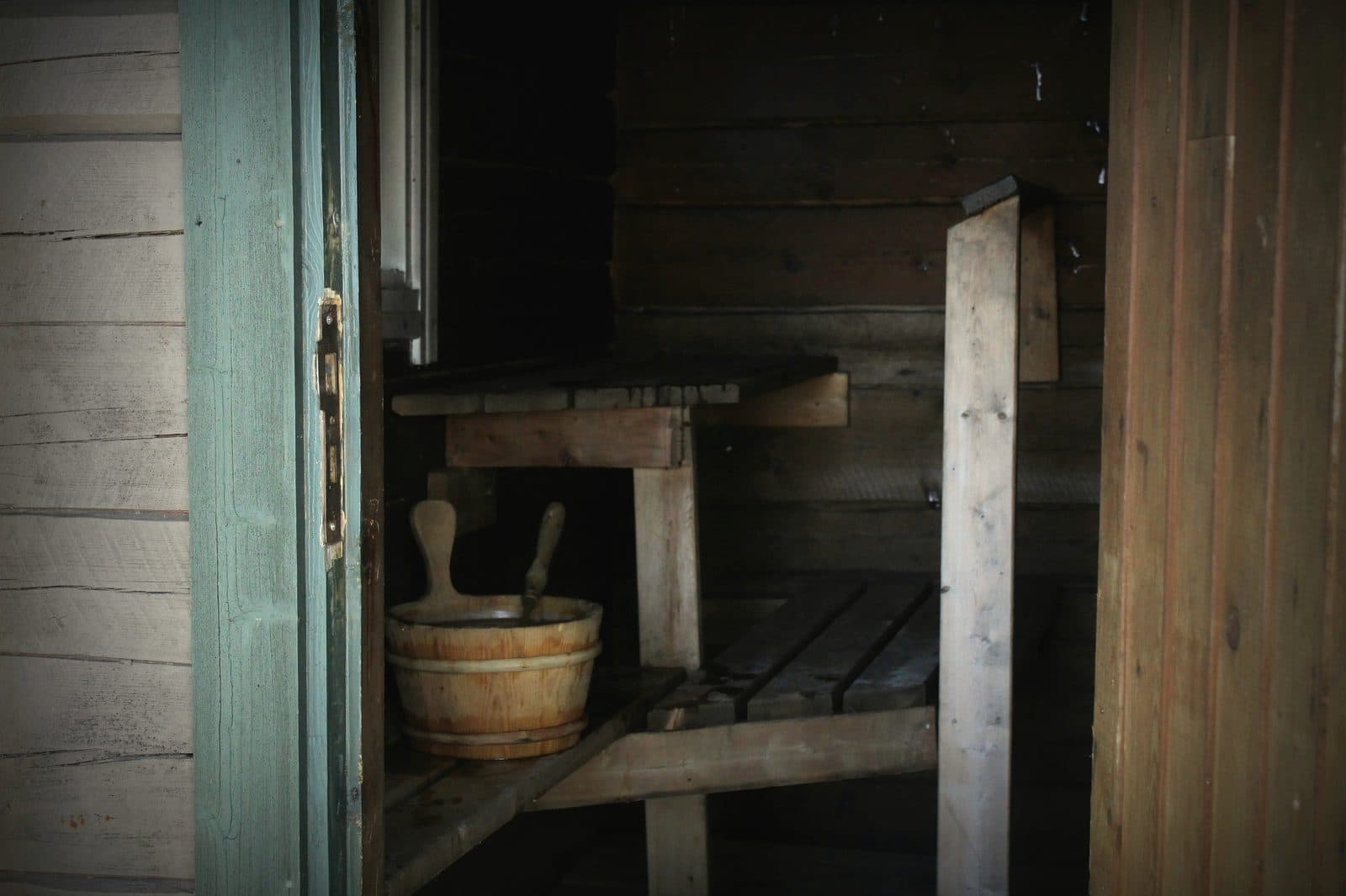 Wooden sauna doorway with a bucket and ladle hanging beside it