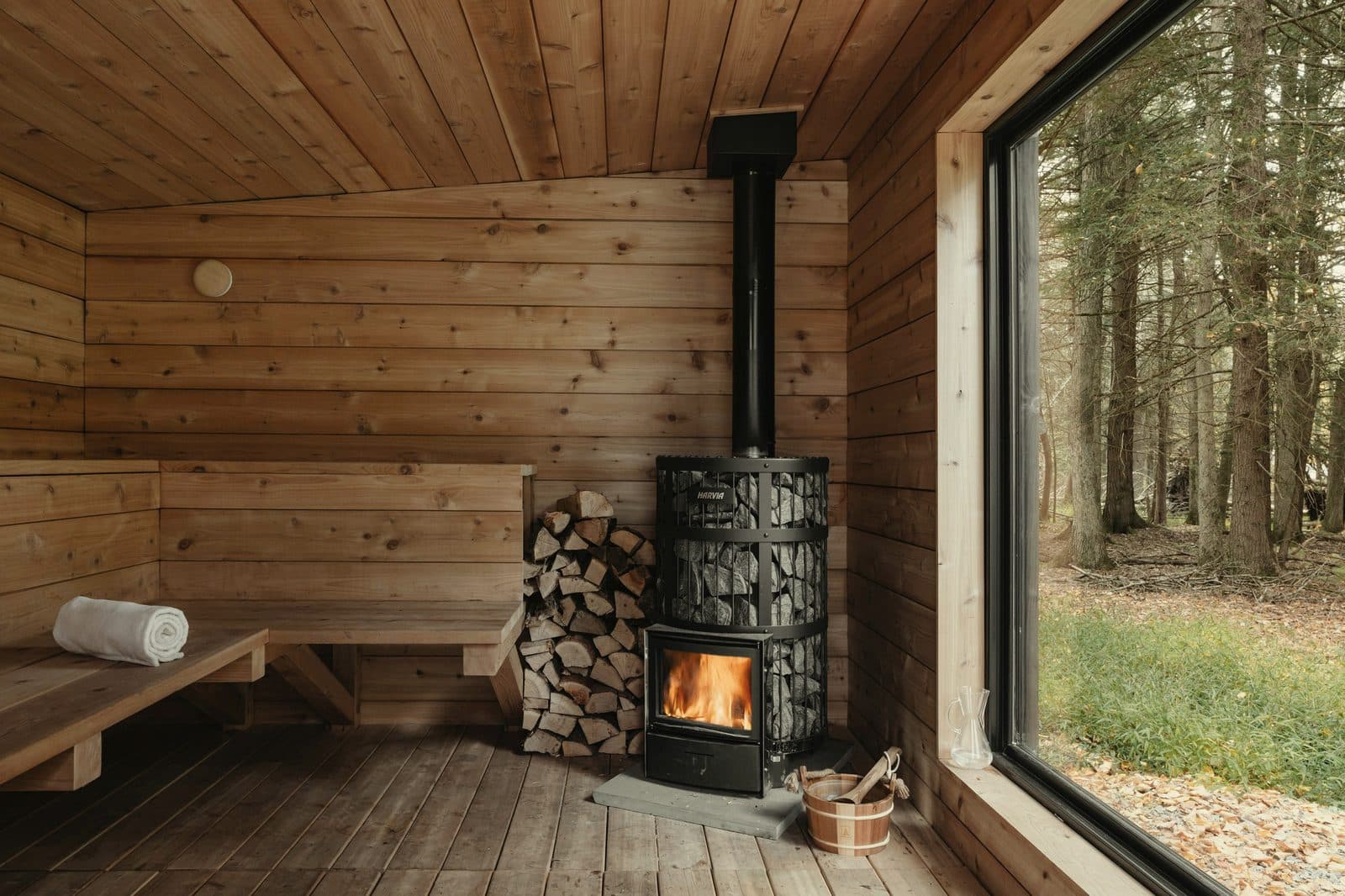 Interior of a woodland sauna cabin showing timber walls and a wood-fired stove