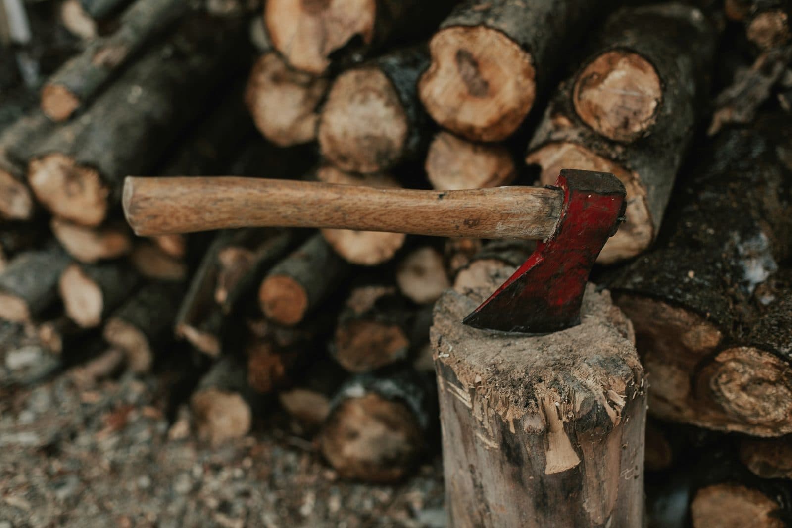 Splitting axe in a chopping block with stacked firewood logs